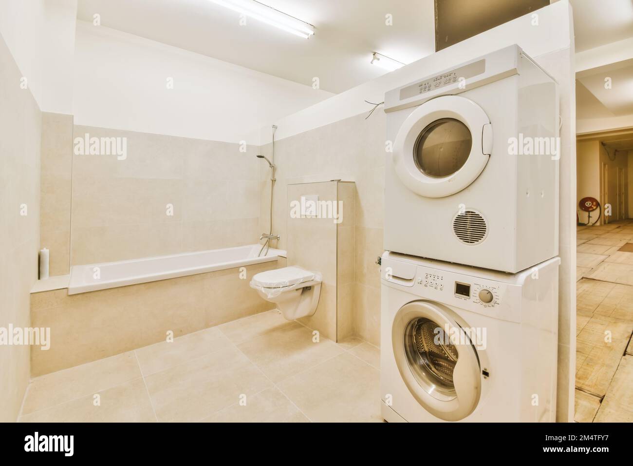 a laundry room with washer, dryer and bathtub in the fore image is