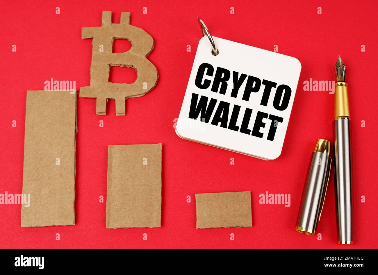 Business and bitcoin concept. On a red surface lie a bitcoin symbol, a graph, a pen and a notepad with the inscription - crypto wallet Stock Photo