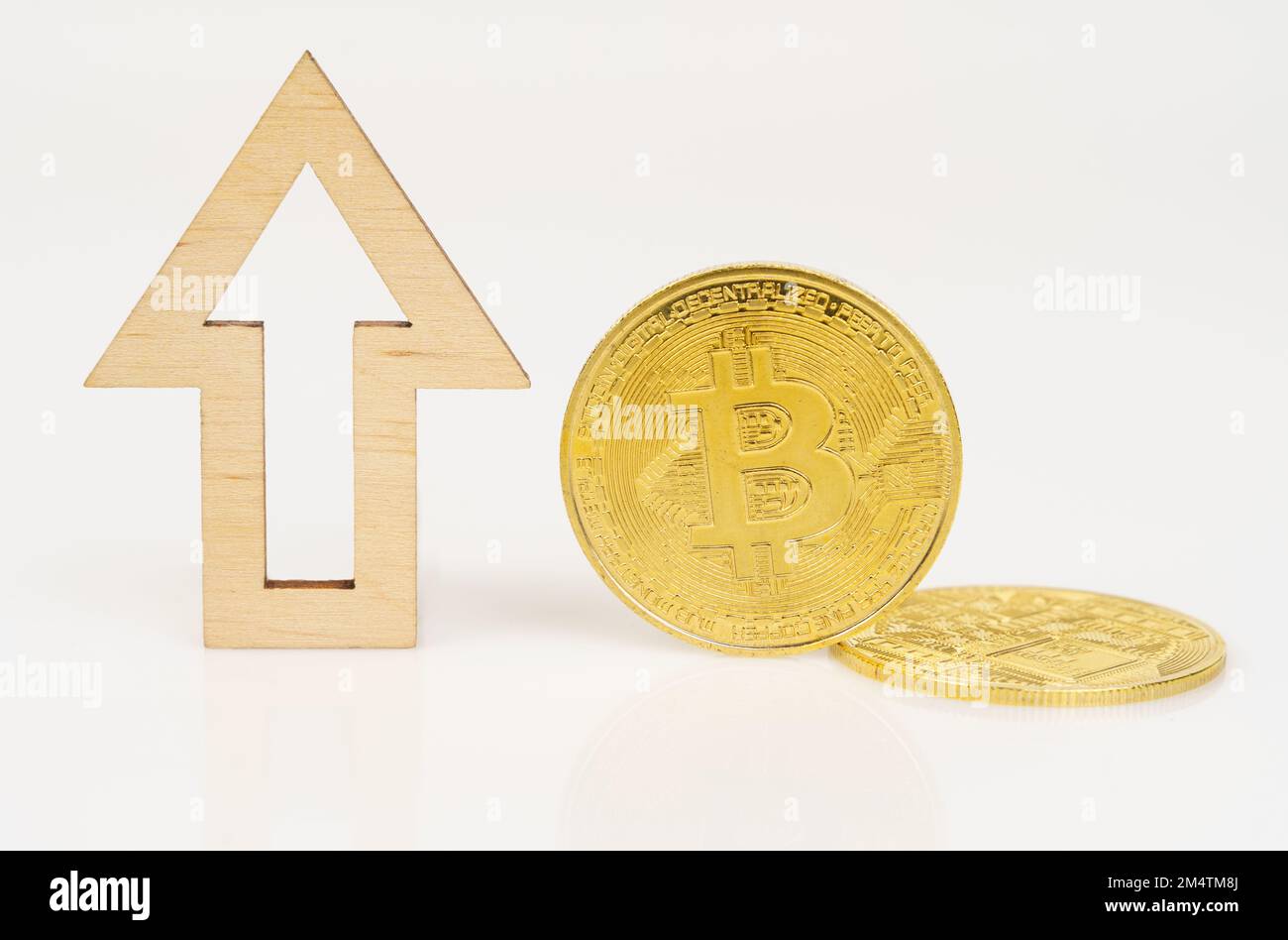 Cryptocurrency and business concept. On a white surface, bitcoin and an arrow showing the growth in the value of the cryptocurrency. Stock Photo