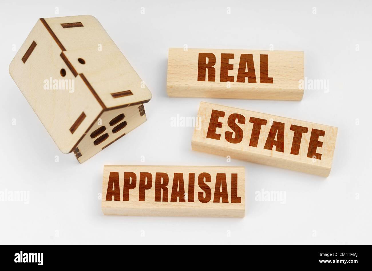 Business and real estate concept. On a white surface, a wooden toy house and blocks with the inscription - Real Estate Appraisal Stock Photo