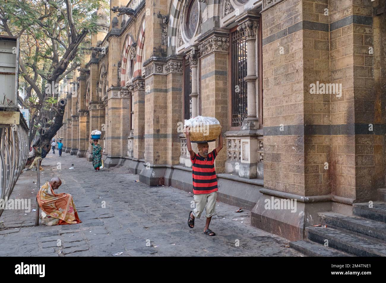 A porter with a basket of fish on his head, at Chhatrapati Shivaji Maharaj Terminus (CMST), in Mumbai, India, to forward the baskets by train Stock Photo