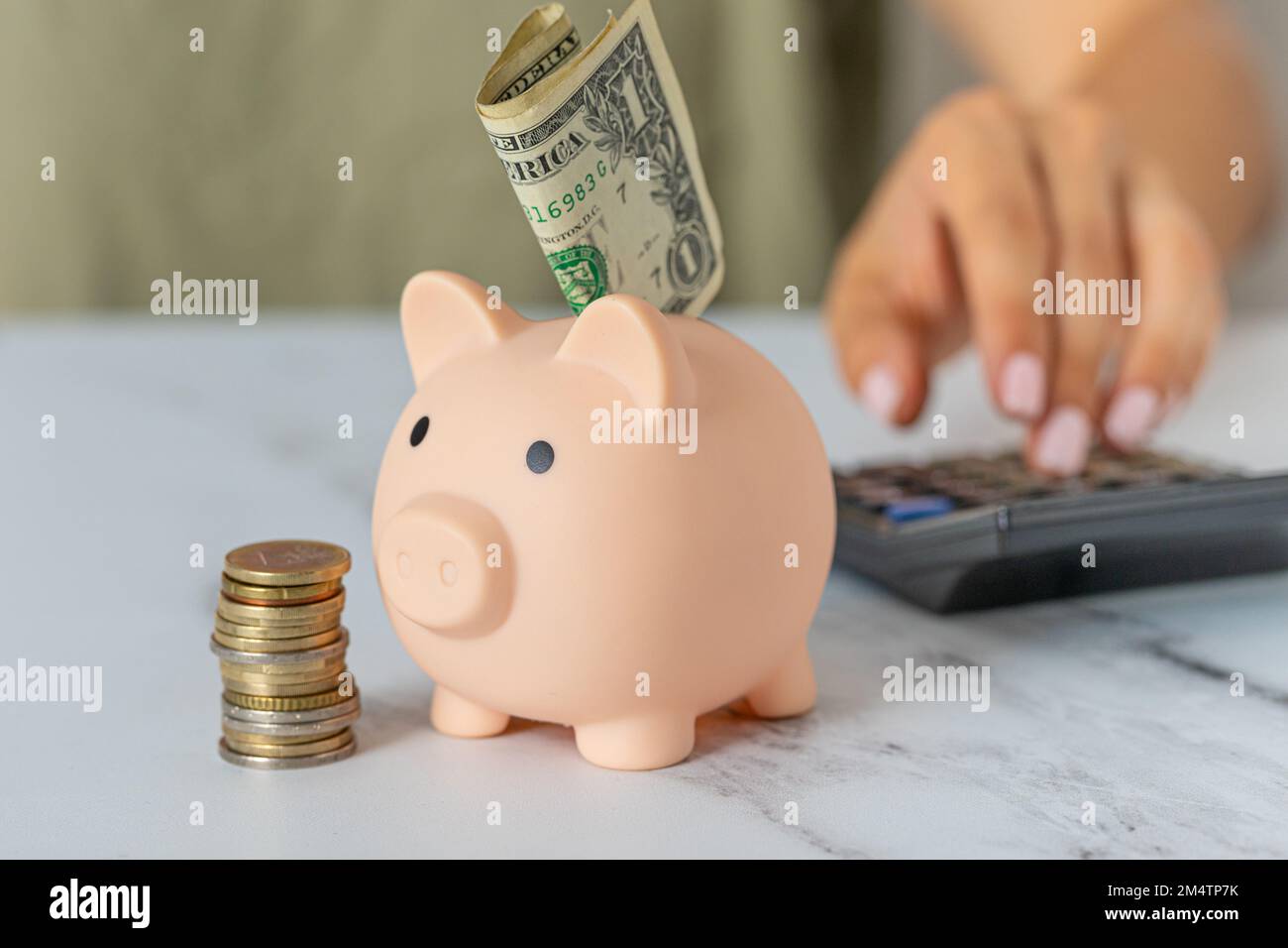 Close-up of a woman's hand with a piggy bank and a calculator on the ...