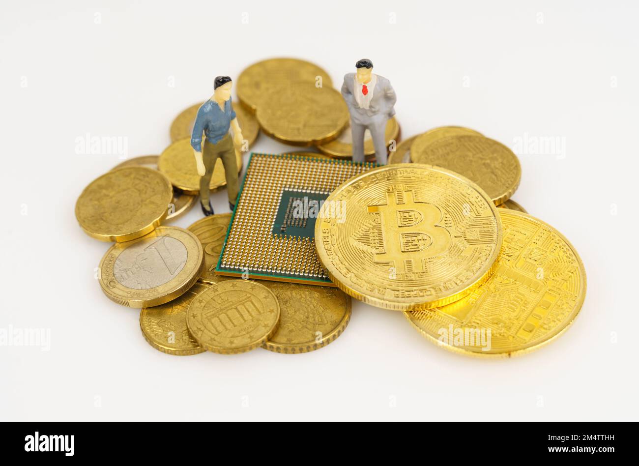 Cryptocurrency and business concept. On a white surface are coins, a processor, bitcoin and miniature figures of people. Stock Photo