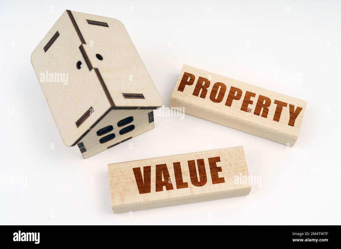 Business and real estate concept. On a white surface, a wooden toy house and blocks with the inscription - Property Value Stock Photo