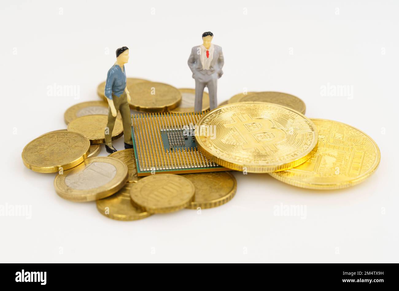 Cryptocurrency and business concept. On a white surface are coins, a processor, bitcoin and miniature figures of people. Stock Photo