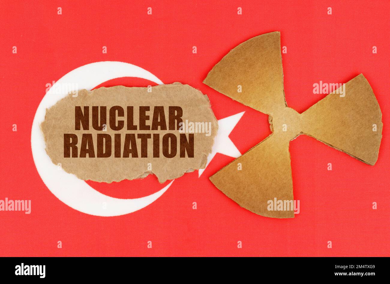 The concept of industry and radiation. On the flag of Turkey, the symbol of radioactivity and torn cardboard with the inscription - Nuclear Radiation Stock Photo