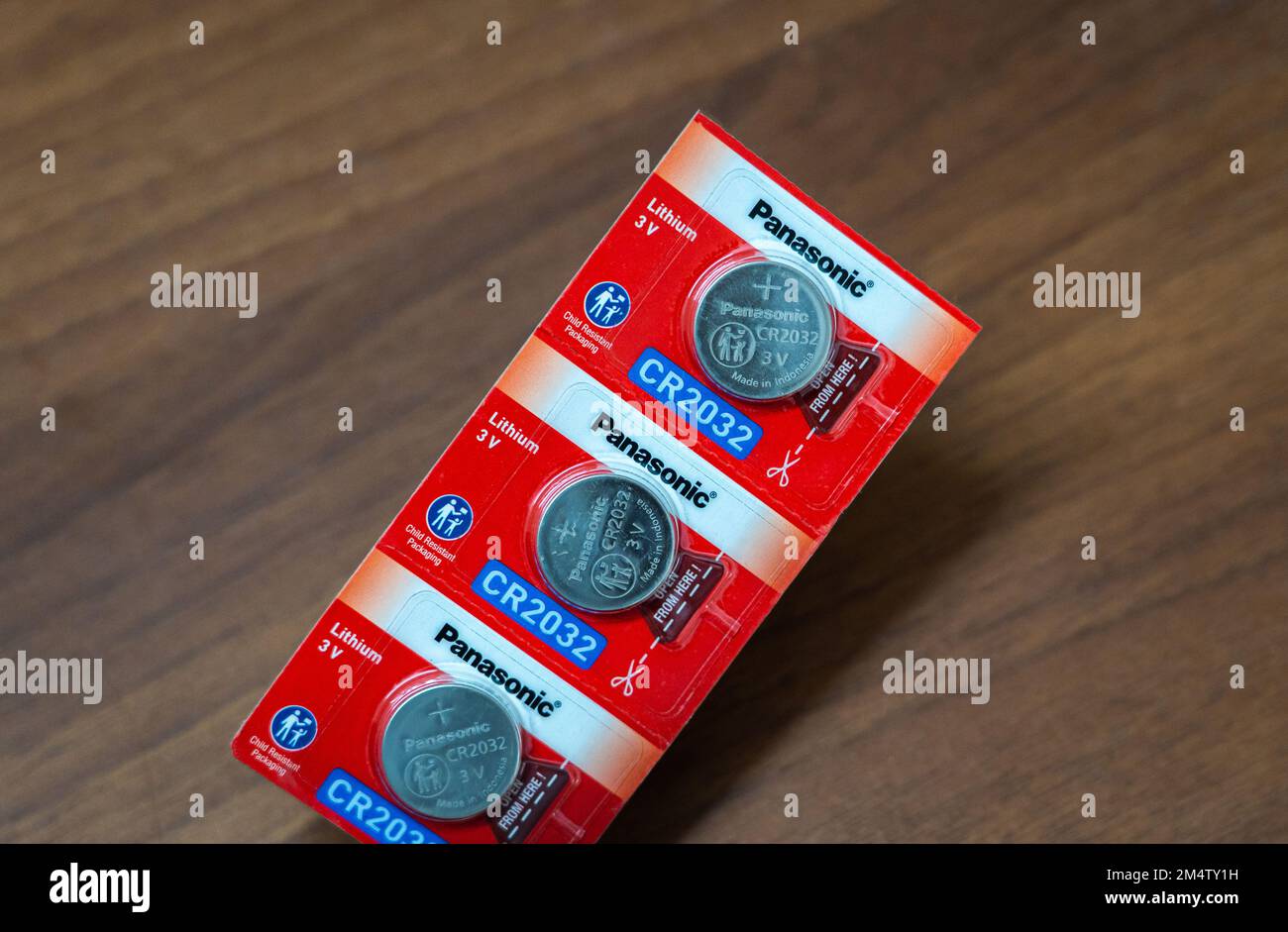 A few sealed Panasonic CR2032 3V coin batteries on wooden background. Stock Photo