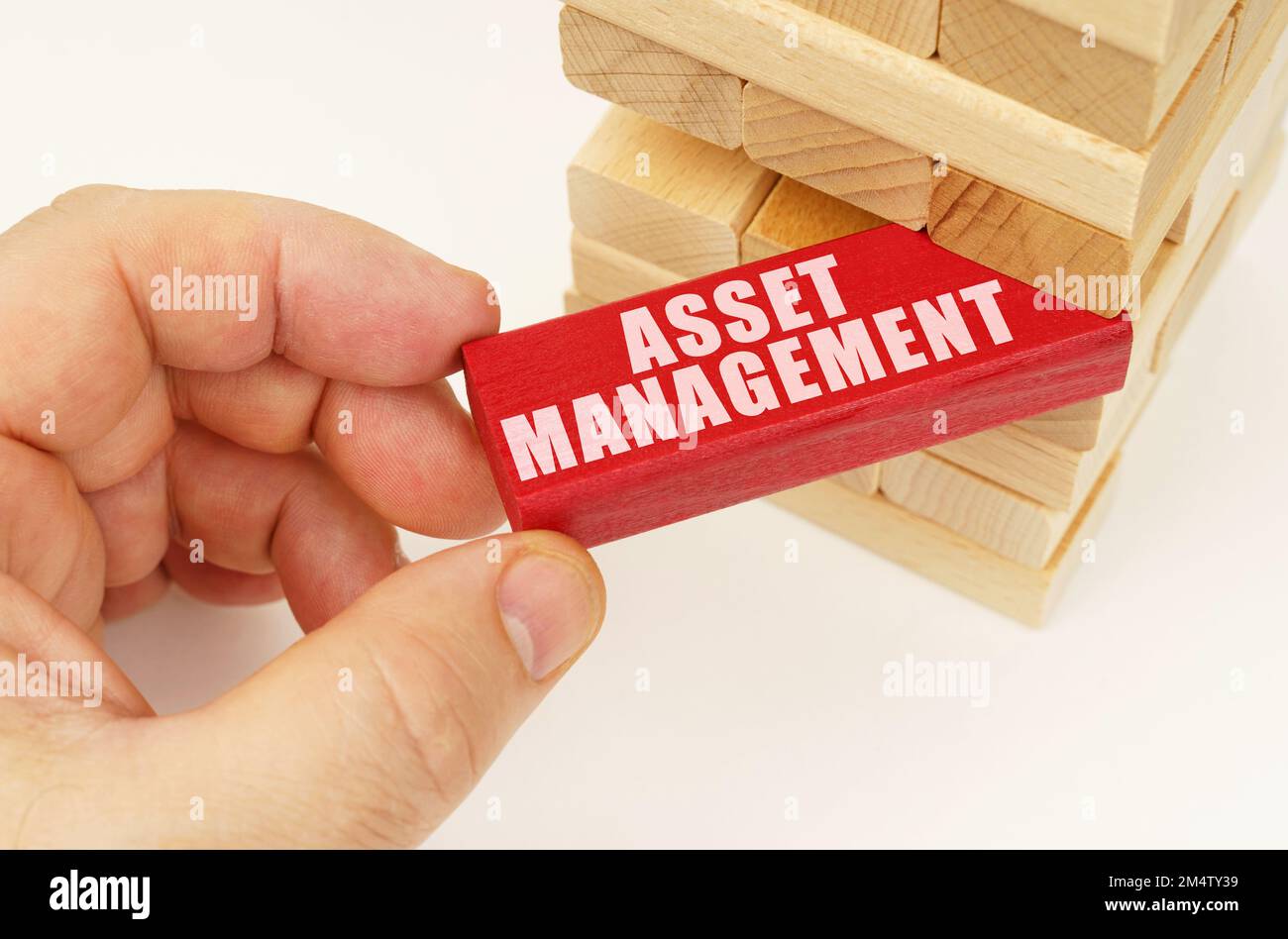 Business and technology concept. From the tower with wooden planks, they take out a red plaque with the inscription - Asset management Stock Photo