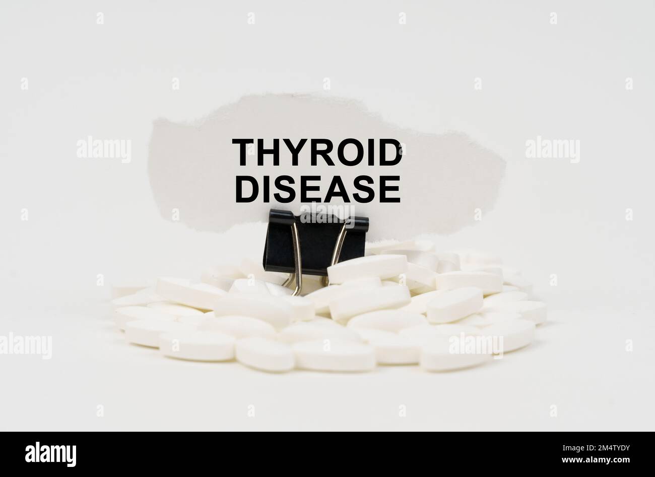 Medical concept. On a white surface are pills and torn paper with the inscription - Thyroid Disease Stock Photo