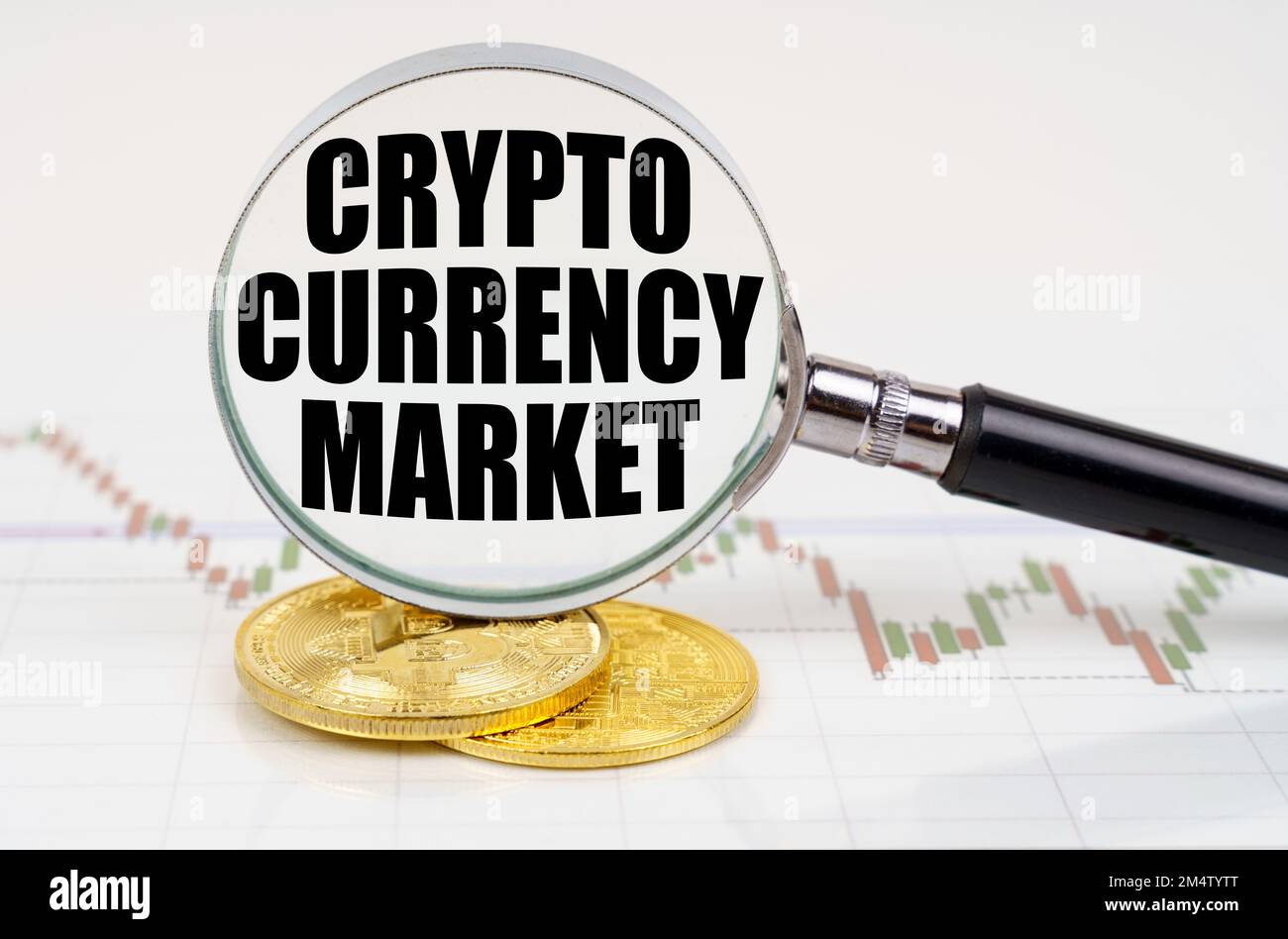 Business and technology concept. On the chart with quotes are bitcoins and there is a magnifying glass with the inscription - Crypto currency market Stock Photo