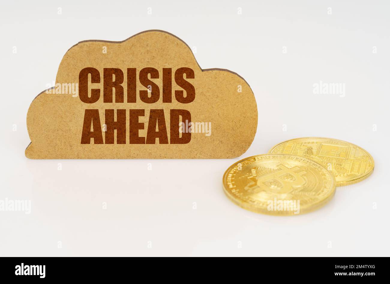 Business and technology concept. Bitcoins lie on a white surface and there is a sign - a cloud with the inscription - CRISIS AHEAD Stock Photo