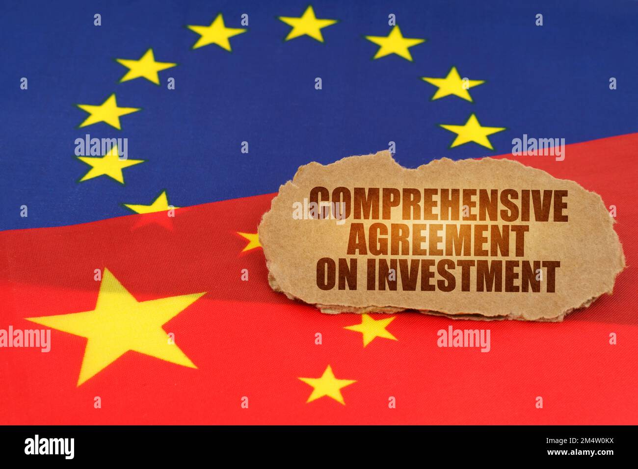 Political concept. On the flags of China and the European Union lies a cardboard plate with the inscription - Comprehensive Agreement on Investment Stock Photo