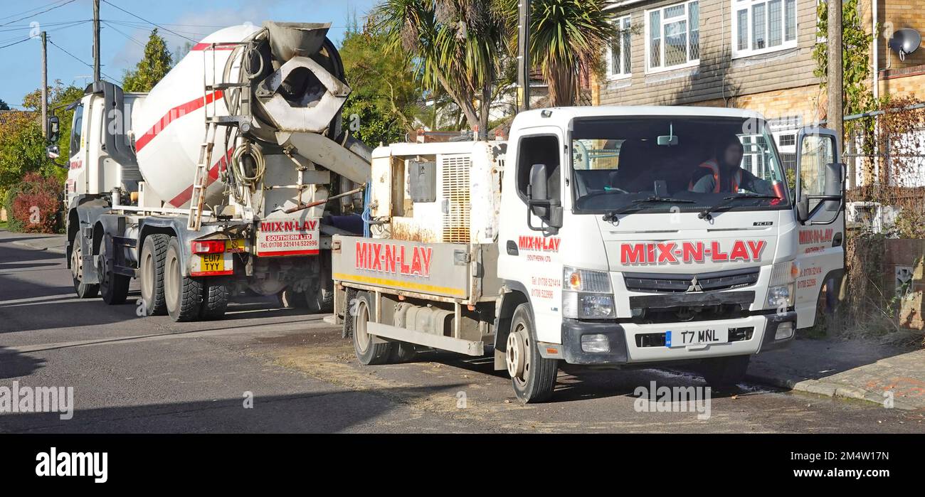 Mix N Lay ready mixed concrete delivery business lorry trucks in residential street pumping into foundations on new detached house on infill plot UK Stock Photo
