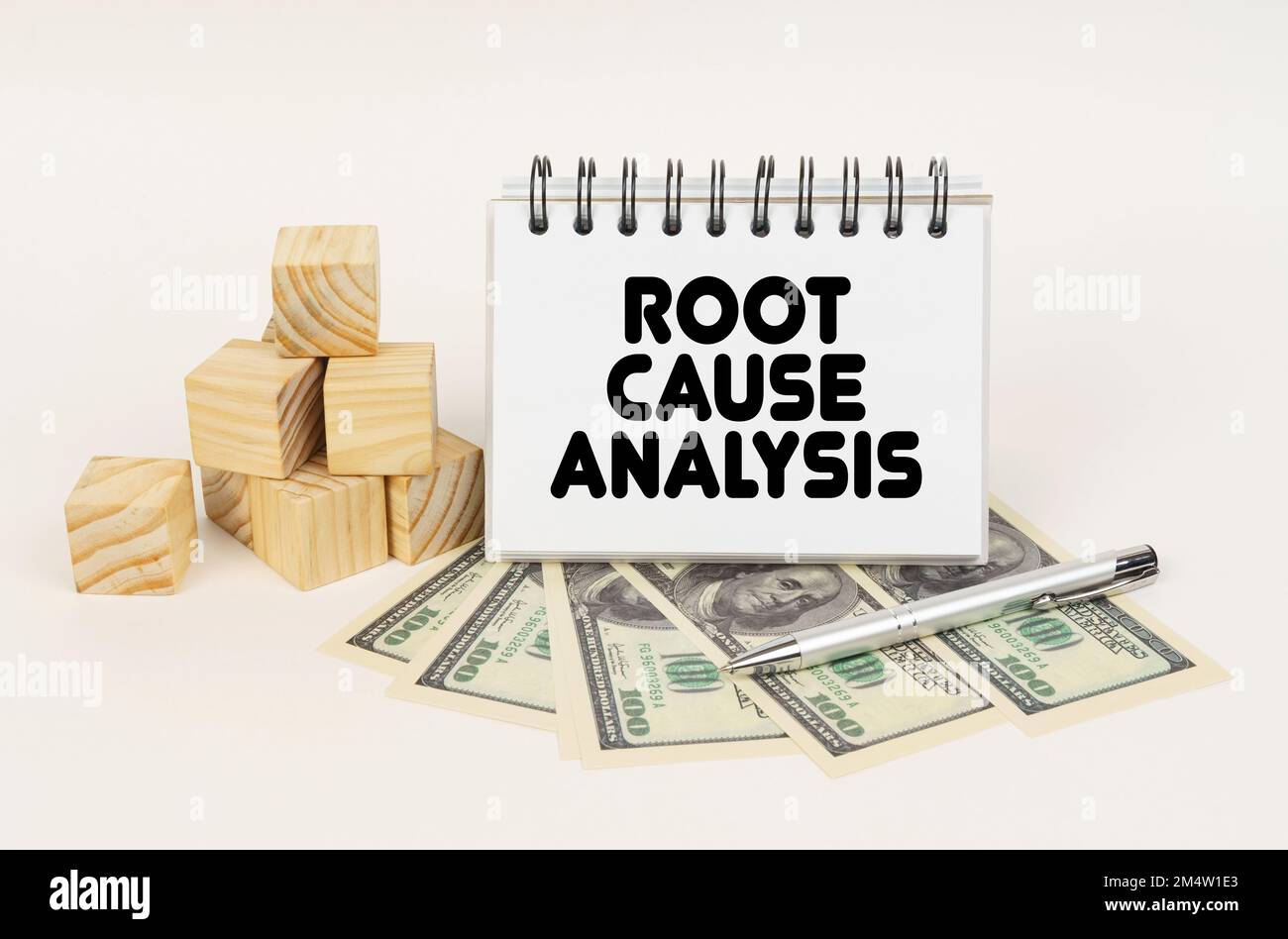 Business concept. On a white surface, cubes, dollars, a pen and a notepad with the inscription - Root Cause Analysis Stock Photo