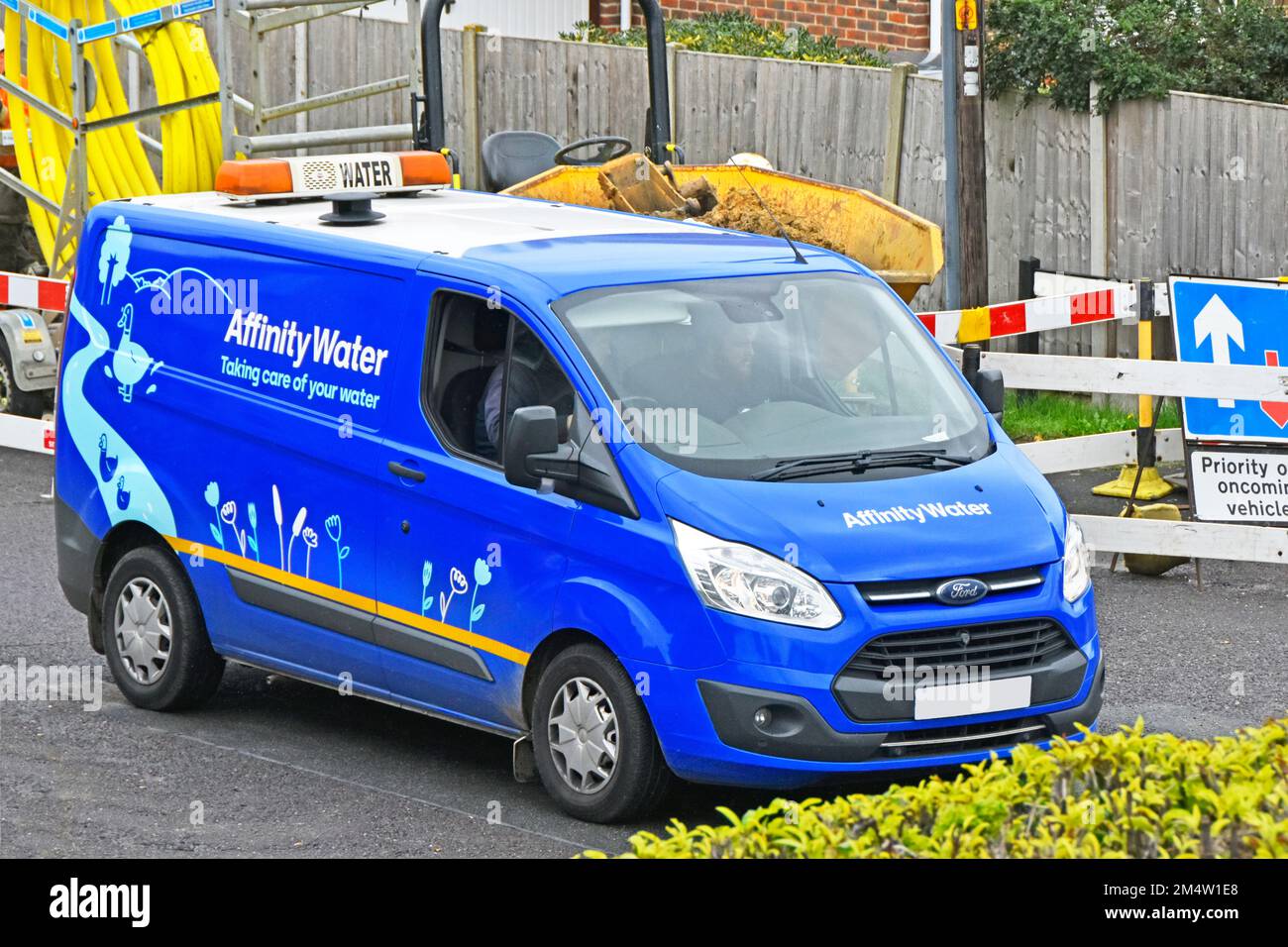 Side & front view Affinity Water supply company business Ford van in residential street driving past gas main replacement road works Essex England UK Stock Photo