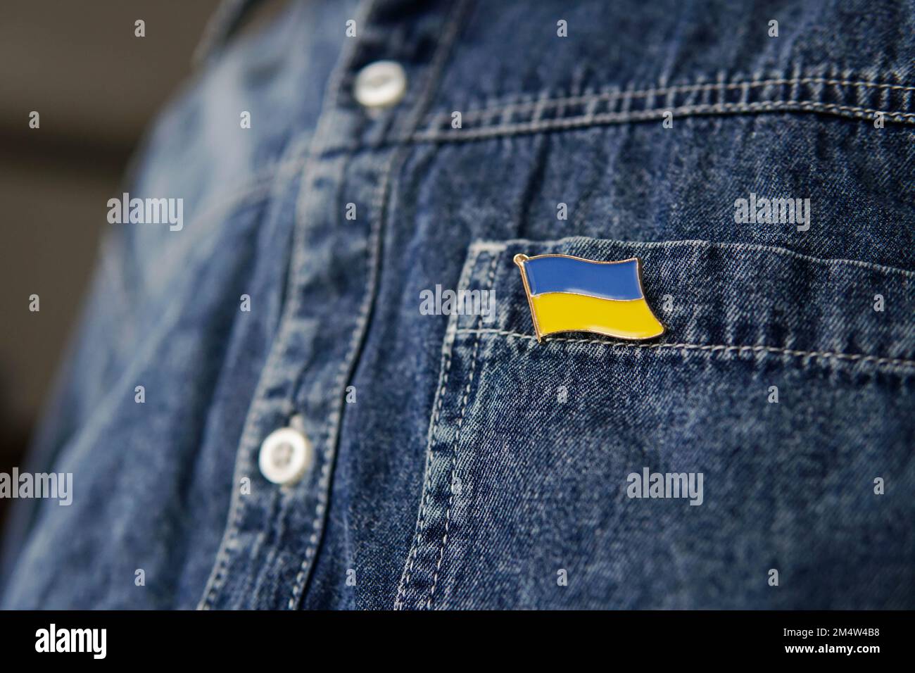 Ukrainian flag icon is pinned on blue jeans jacket. Support for Ukraine. War in Ukraine. Stock Photo
