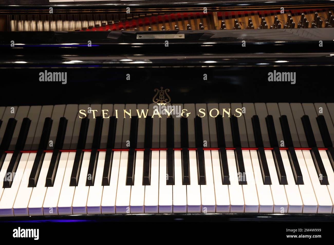 Keyboard of a shiny black piano with brand name visible: Steinway & Sons Stock Photo
