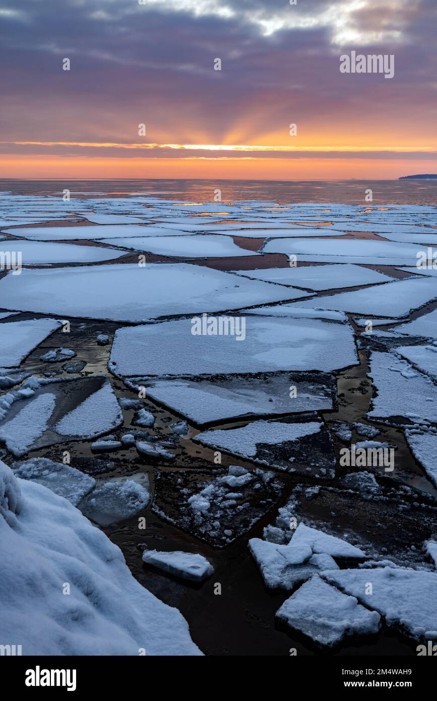 Ice floes floating on the surface of Lake Superior under a beautiful sunrise as day begins to break and the winter breakup begins. Stock Photo