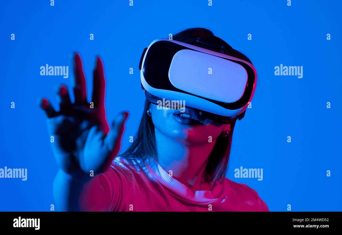 Brunette woman wearing VR virtual reality headset touching air during ...