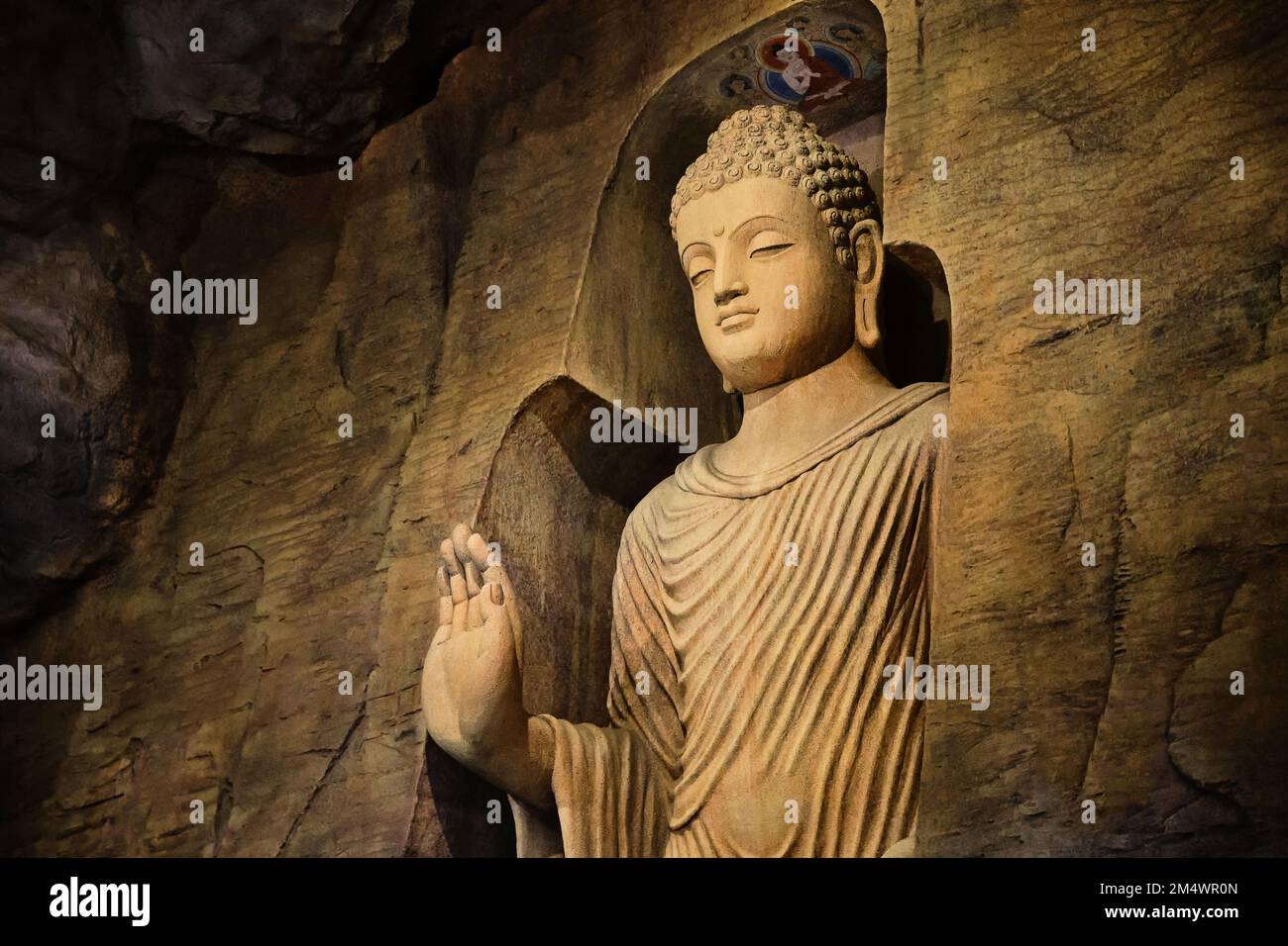 Statue of standing Buddha in monk clothes carved in limestone cave Stock Photo Alamy