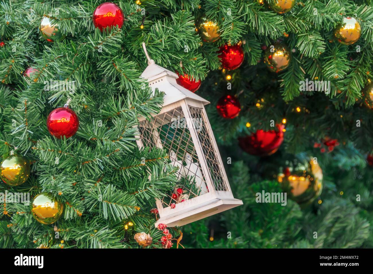Lantern and candles as a Christmas decoration on the branches of a spruce, red balls, cones and berries, Christmas background Stock Photo