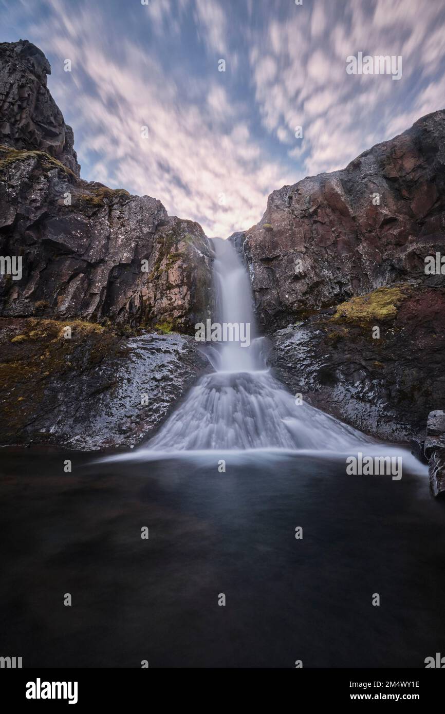 A vertical long exposure shot of the Klifbrekku Waterfall in Iceland ...