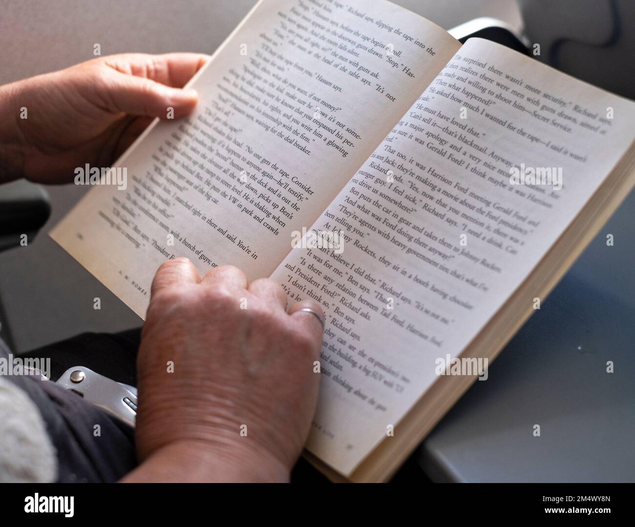 A woman reads a book while on an airplane. Stock Photo