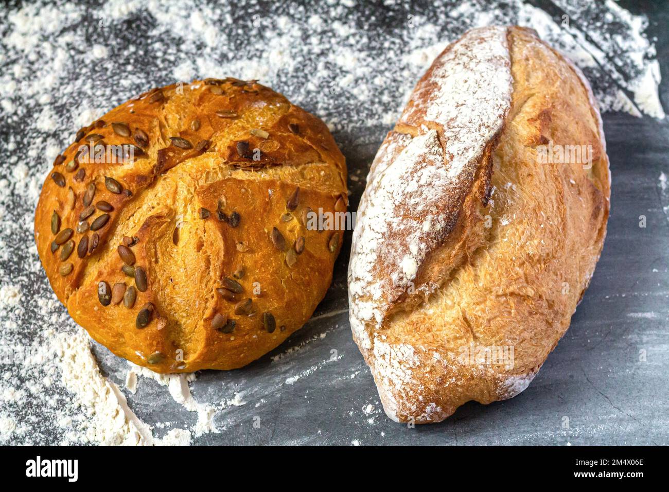 Bakery background with two different freshly baked crispy bread on flour kitchen table Stock Photo