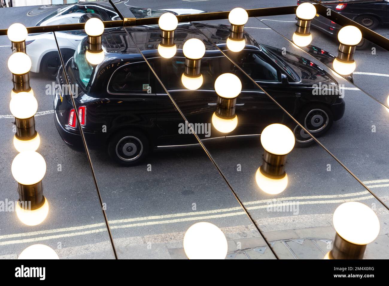 A Black london Cab is reflected in theatre lights shining into mirrors on the theatre ceiling.An unusual image and a unique angle of a London Taxi Stock Photo