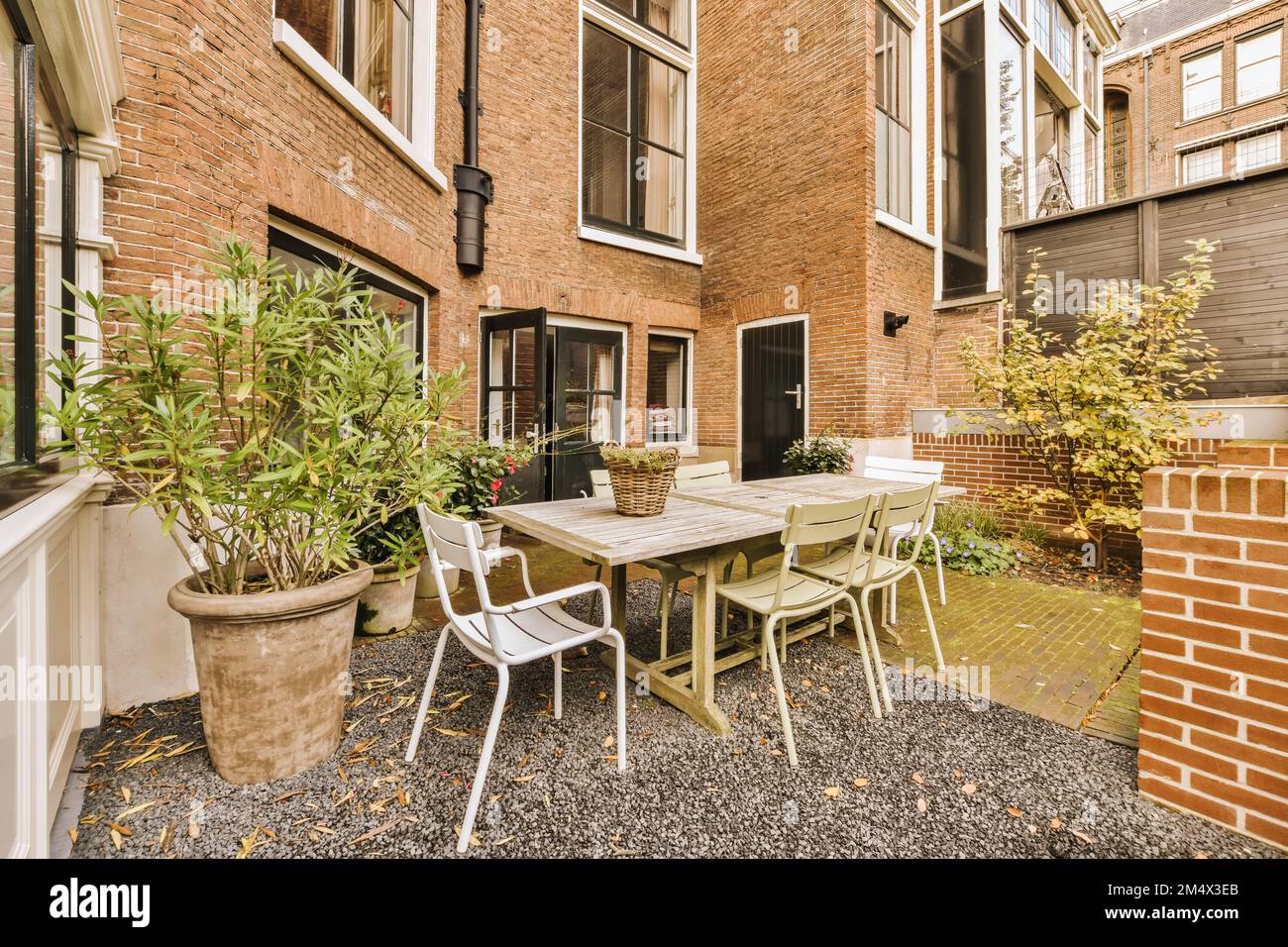a patio with chairs, table and potted plants on the ground in front of ...