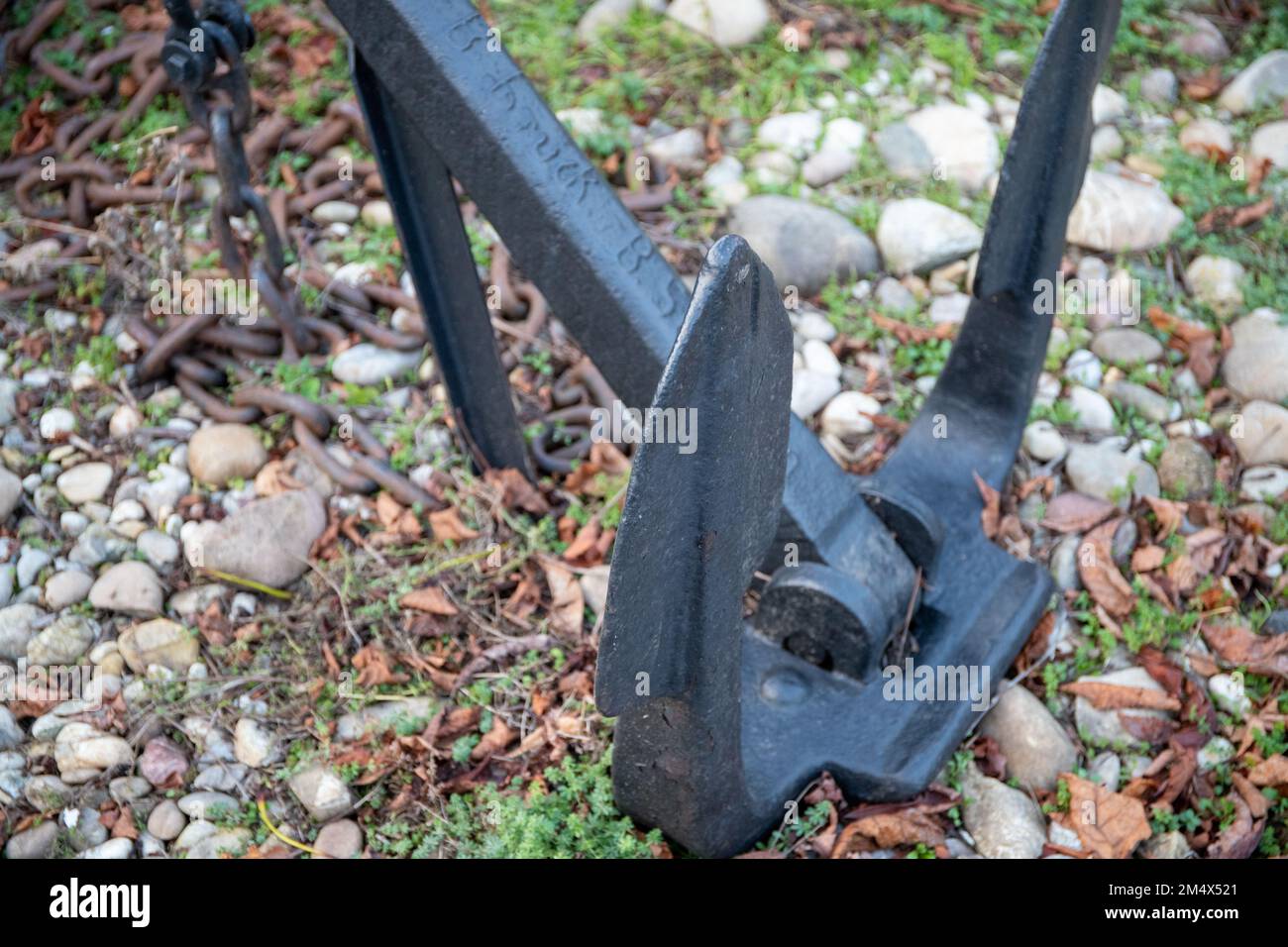 Massive anchor on land on stones with a chain. Stock Photo