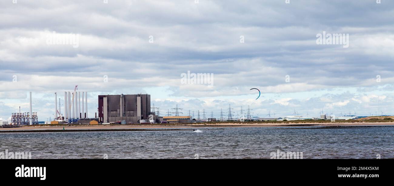 A male kite surfer rides the waves at Redcar,England,UK with Teesport and Hartlepool Power Station in the background Stock Photo