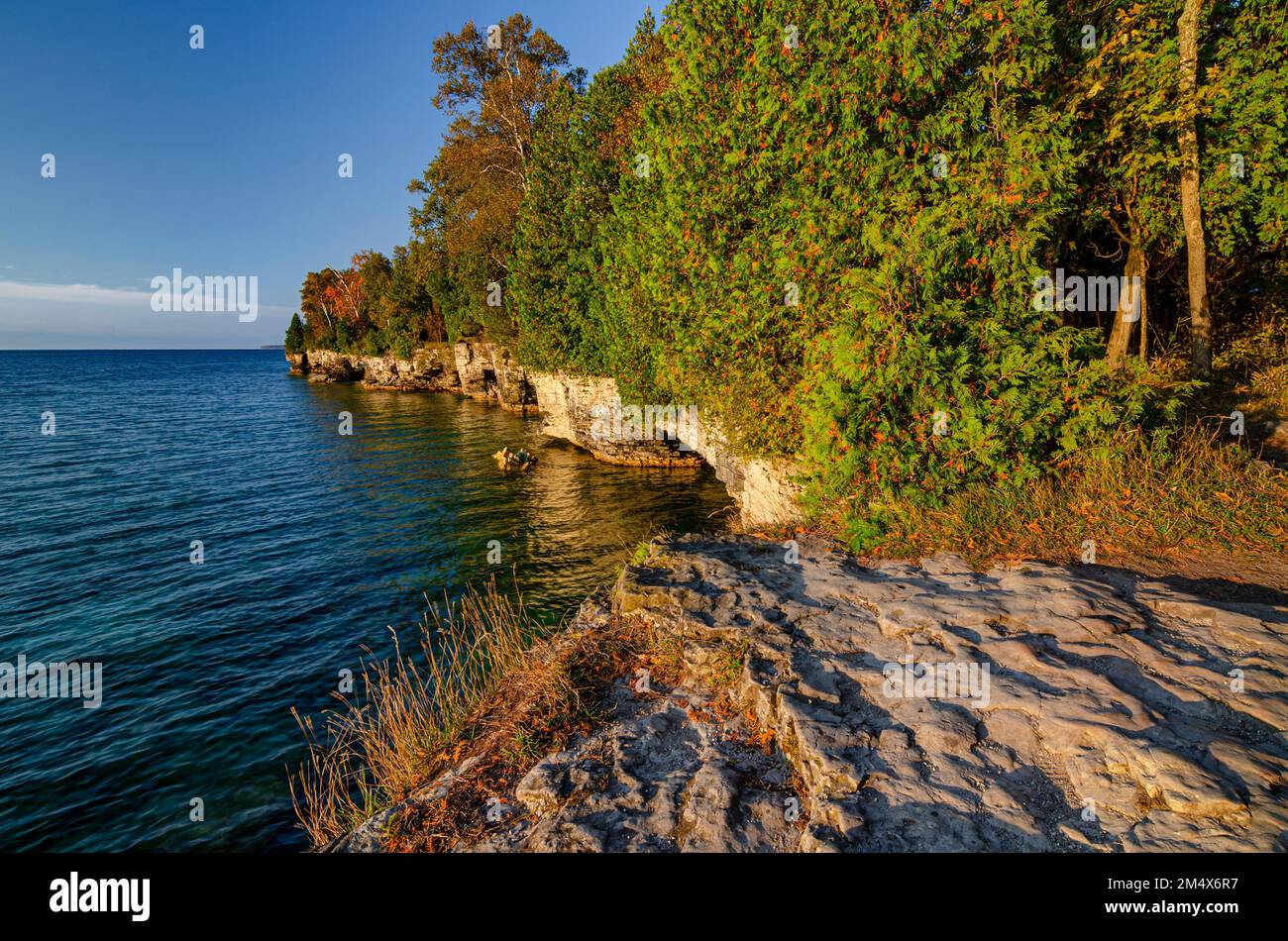 The Cave Point bluff shore is lit with early light in autumn, Cave Point County Park, Door County, Wisconsin Stock Photo