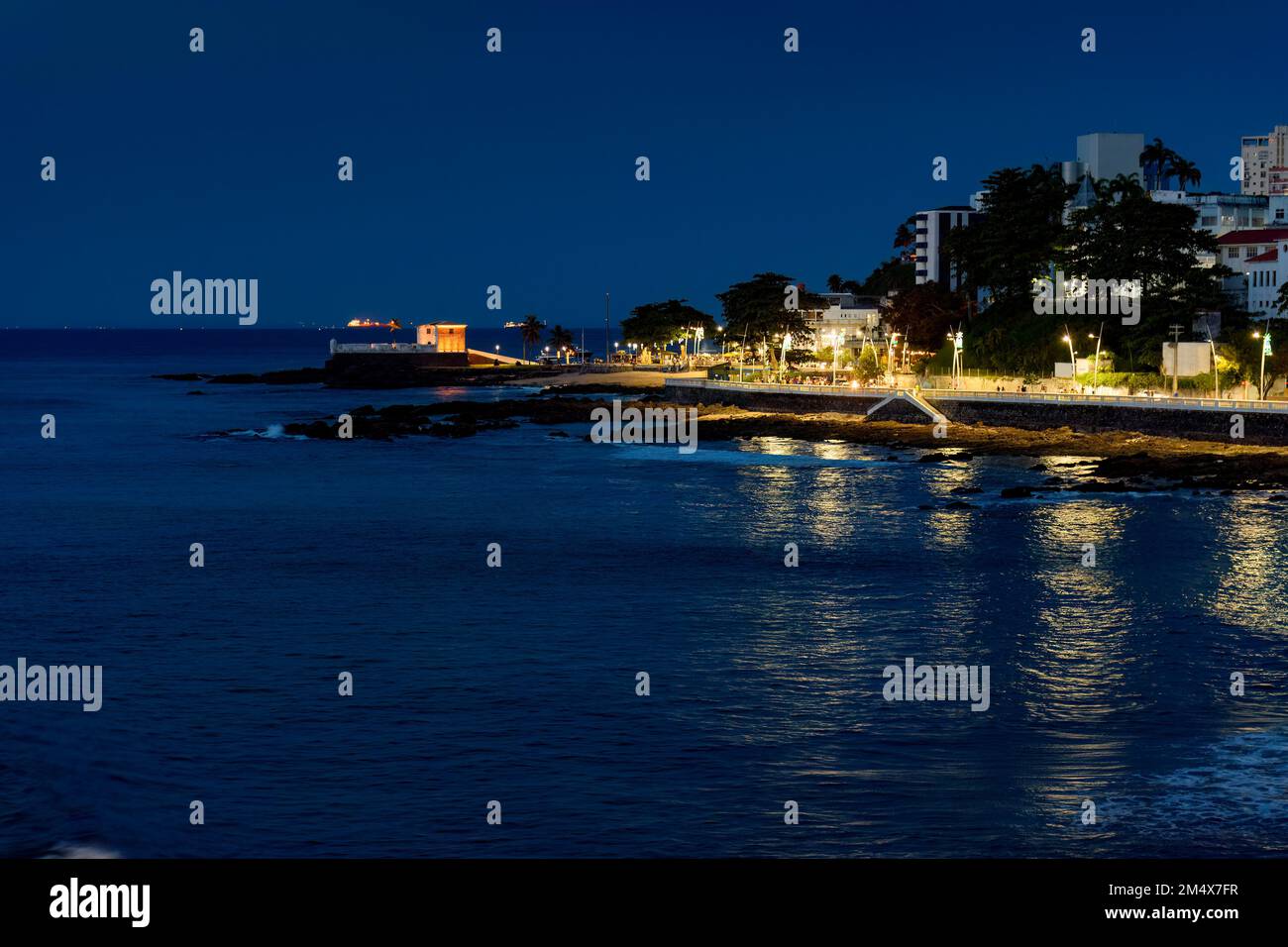 Night at Barra beach in Salvador in Bahia illuminated by city lights with reflections on the water Stock Photo