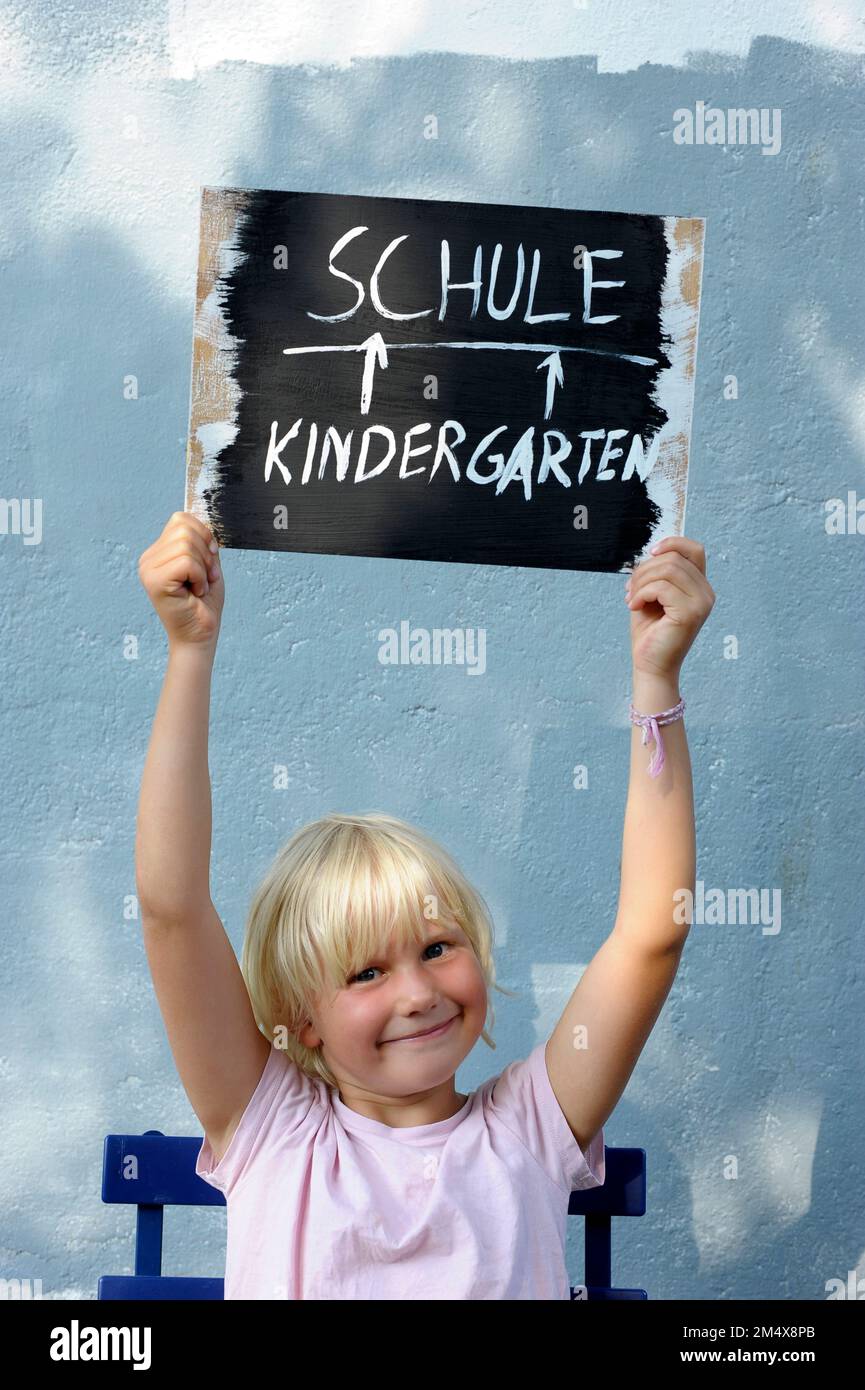 Portrait of little girl holding aloft chalkboard Stock Photo