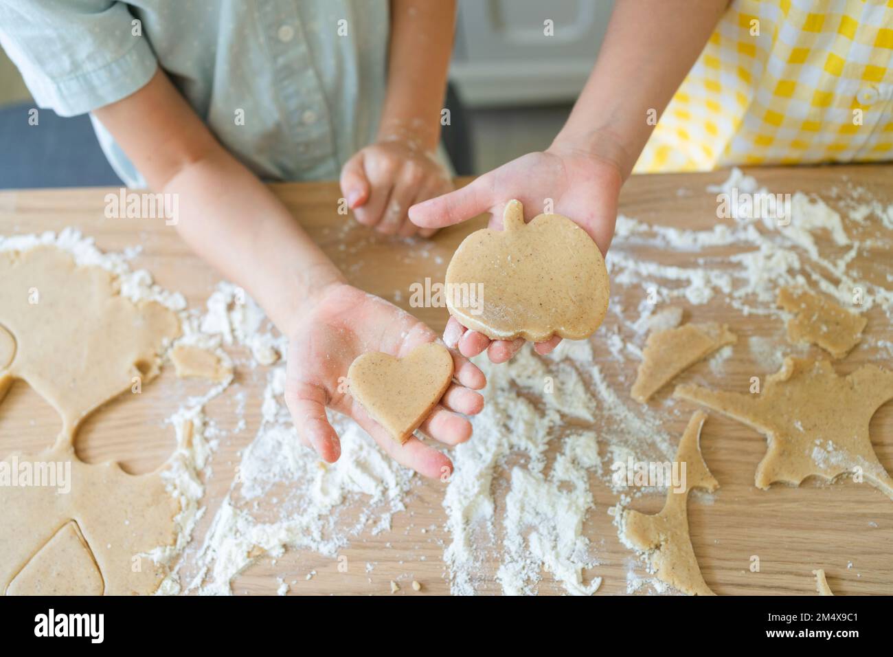 Hand of girl and mother holding cookie dough on table at home Stock Photo