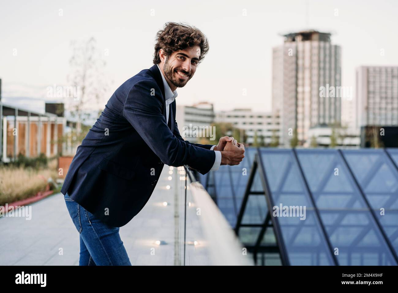 Smiling young businessman leaning on railing Stock Photo