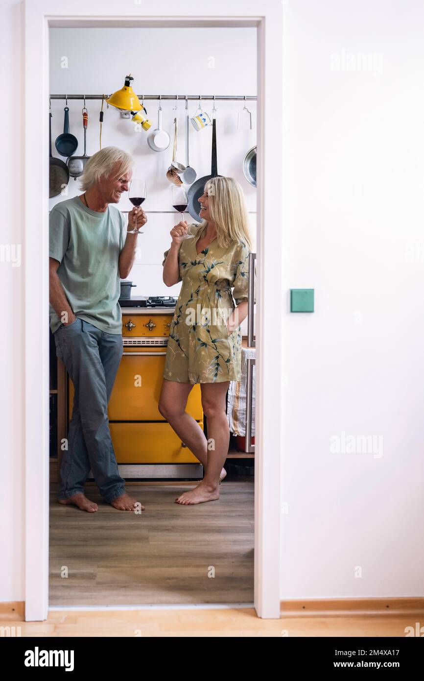 Happy couple drinking red wine in kitchen Stock Photo