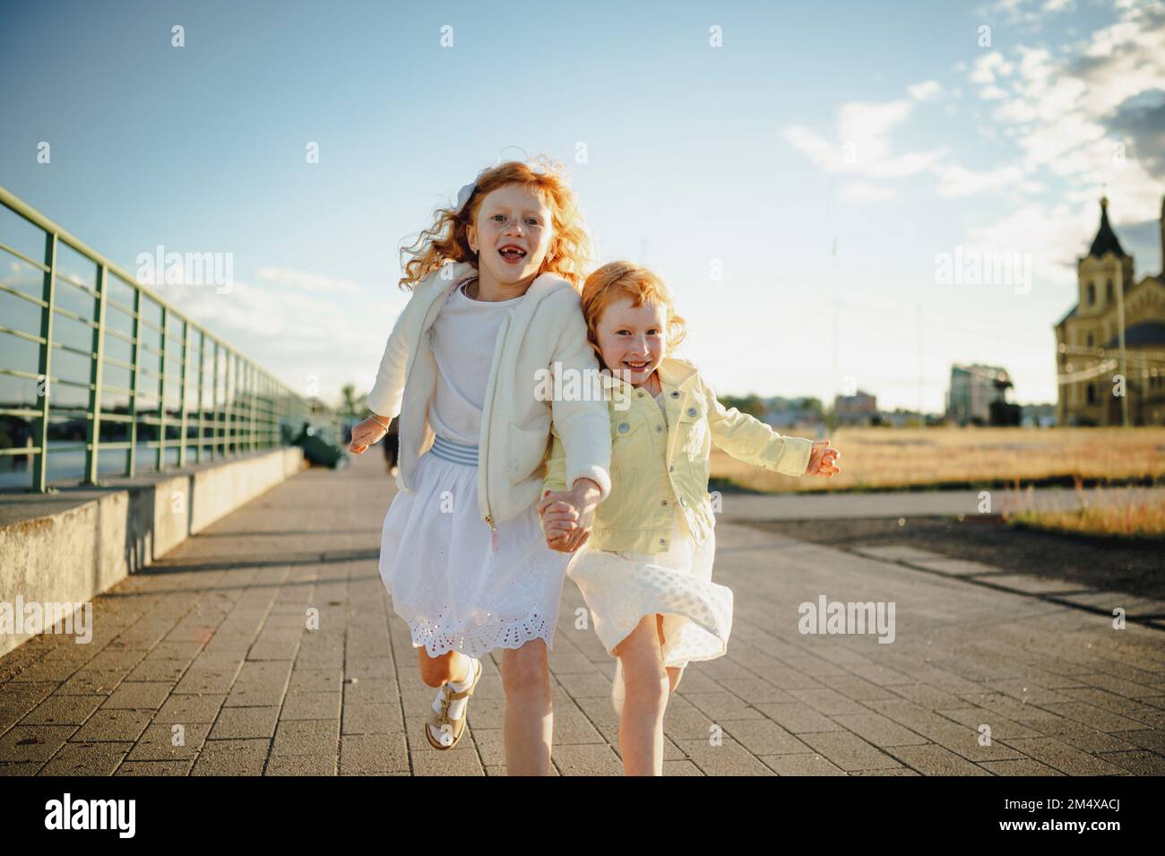 Happy girls holding hands and running on footpath Stock Photo - Alamy