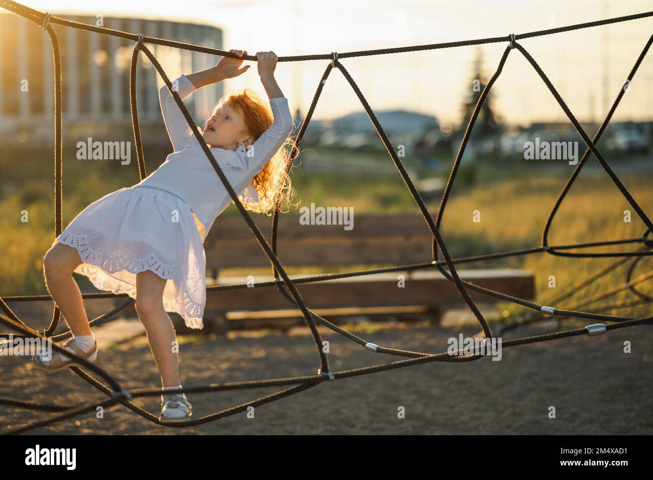 Girl climbing rope ladder in park Stock Photo