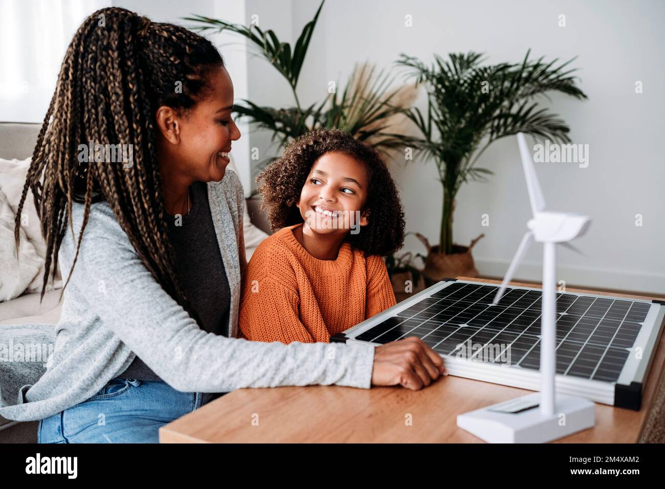 Smiling mother and daughter with sustainable energy generators at home Stock Photo