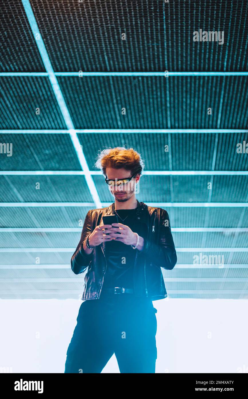 Young man wearing smart glasses using mobile phone at underpass Stock Photo