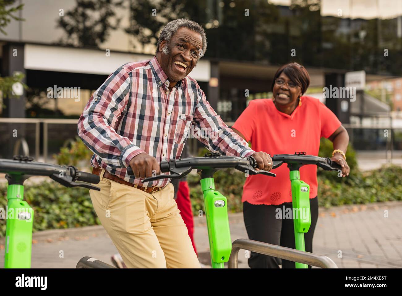 Cheerful senior couple enjoying with each other holding push scooters Stock Photo