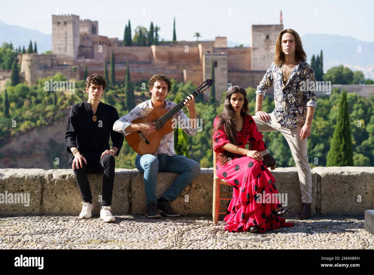 Flamenco musicians and dancers sitting on wall in front of Alhambra, Granada, Spain Stock Photo
