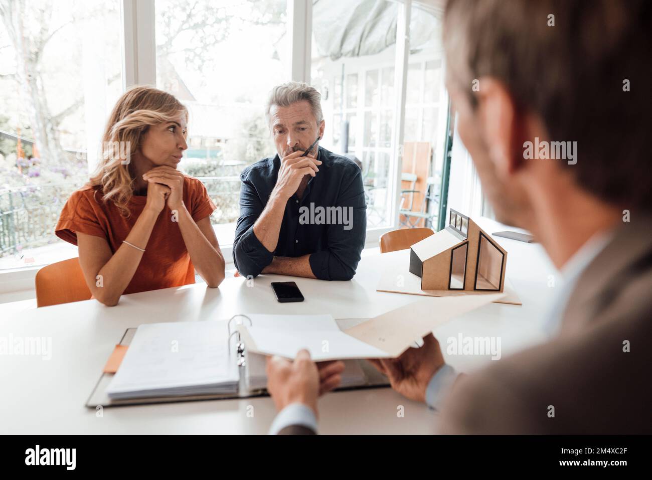 Mature couple discussing over documents with real estate agent at table Stock Photo