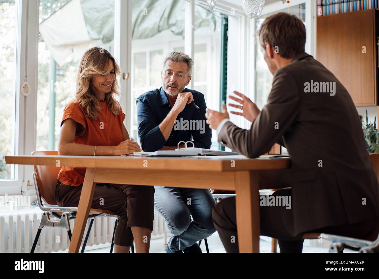 Smiling mature couple discussing over documents with real estate agent at table Stock Photo