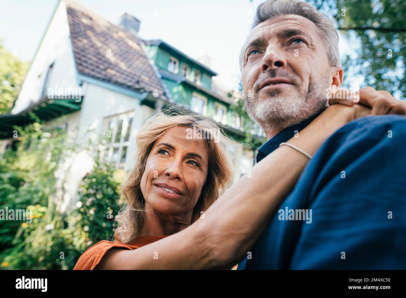 Happy mature woman hugging man in front of house Stock Photo