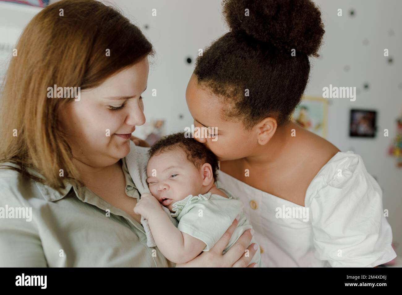 Happy mother with daughter kissing baby girl at home Stock Photo