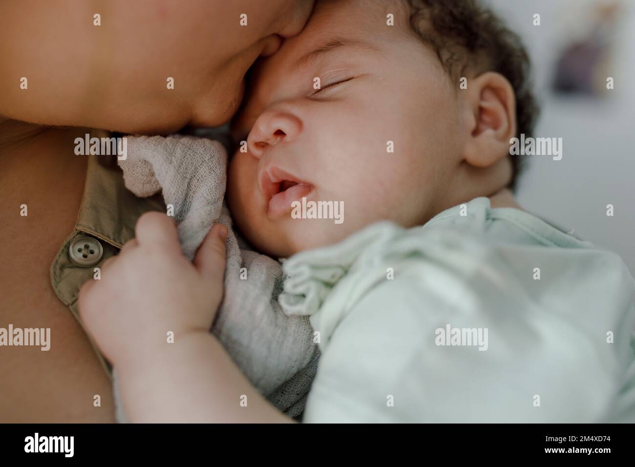 Mother kissing newborn baby girl on forehead at home Stock Photo