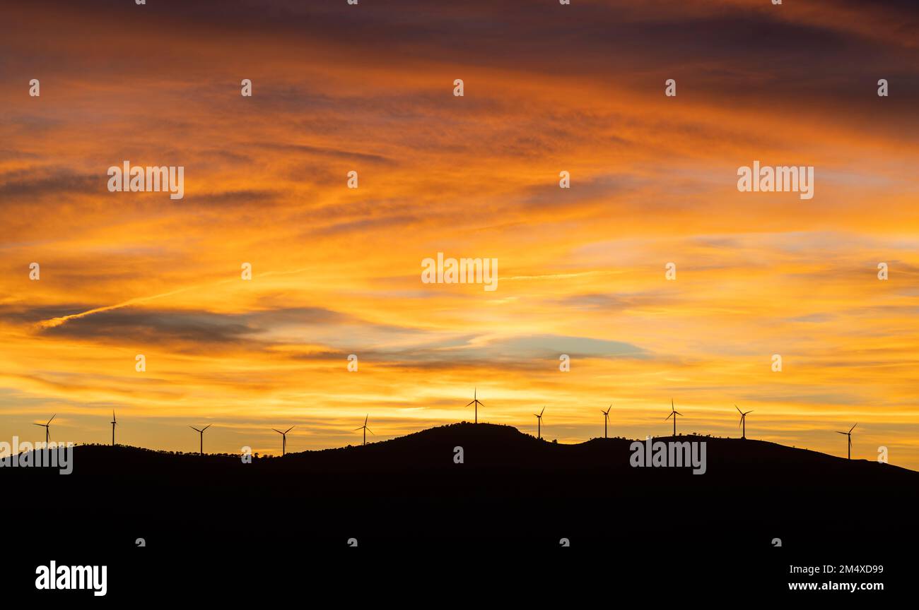 Moody sky over silhouettes of wind farm turbines at sunset Stock Photo ...